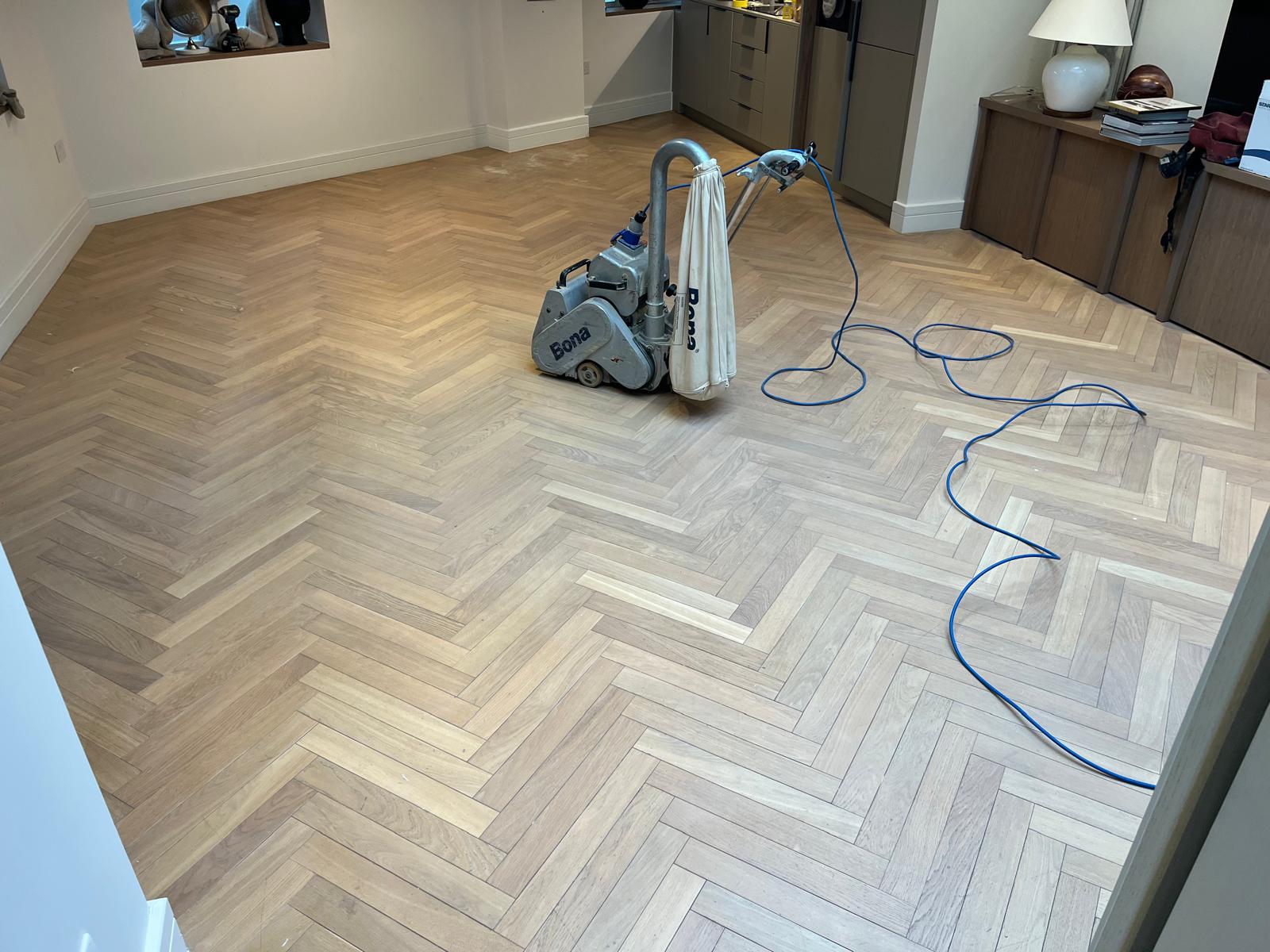 Parquet Floor Sanding in Hackney on an oak herringbone parquet living room floor with a professional Bona sanding machine in use.
